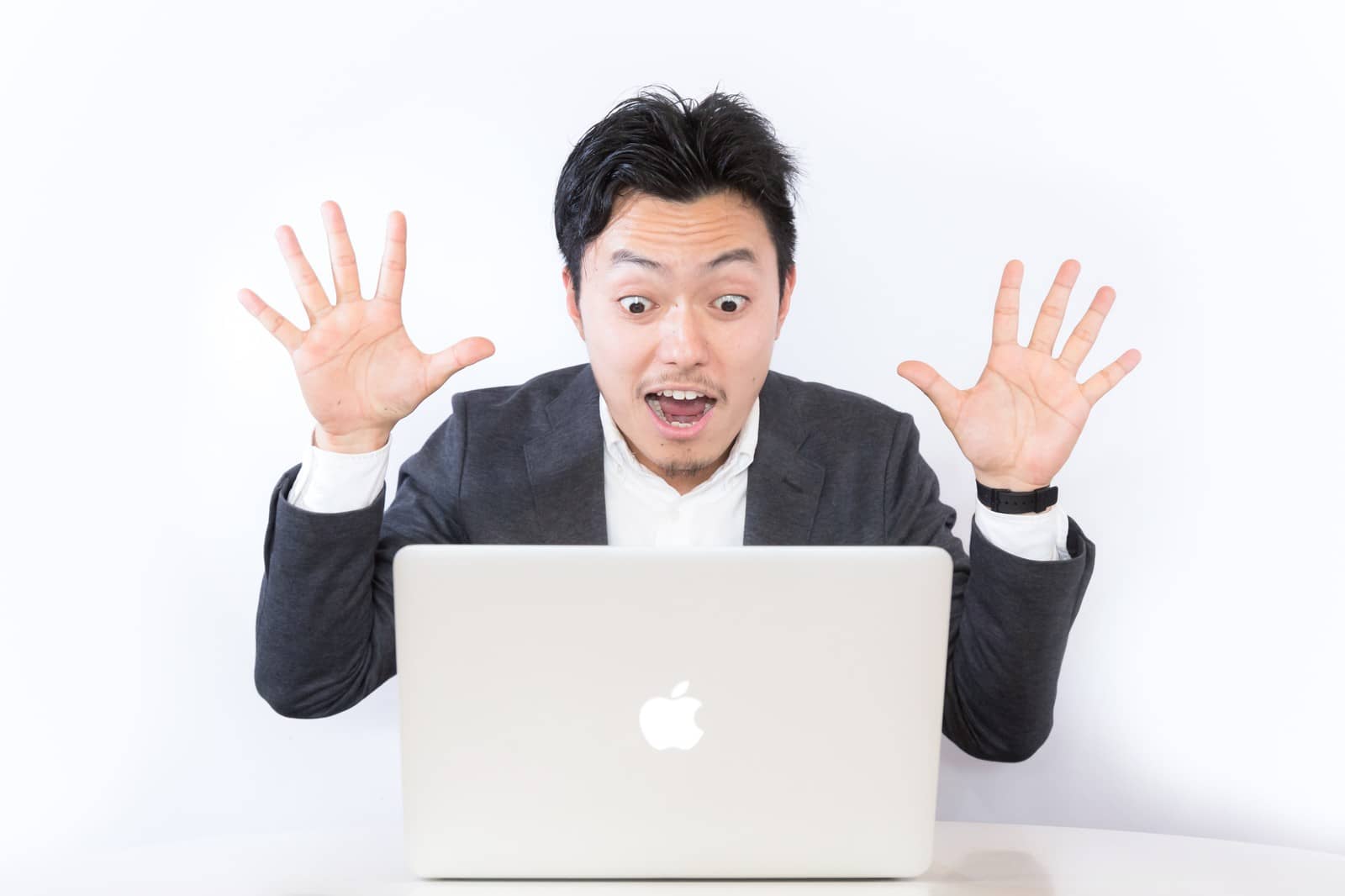 パソコンの前で驚いている男性の画像